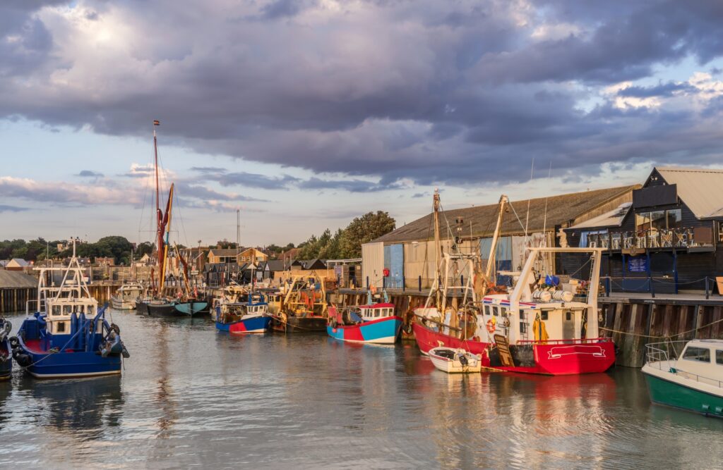 View of Whitstable Harbour with fishing boats and beach huts — local landmark near homes we assess for Energy Performance Certificate Whitstable services.